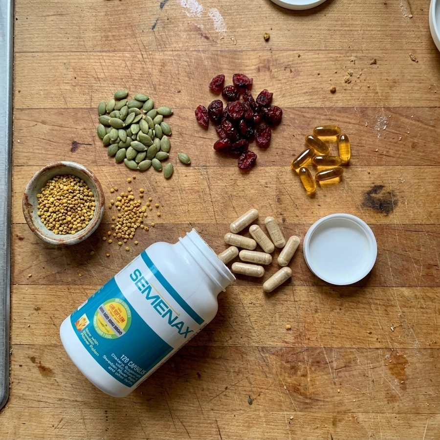 Pumpkin seeds, dried cranberries, flower pollen and capsules on a wooden counter